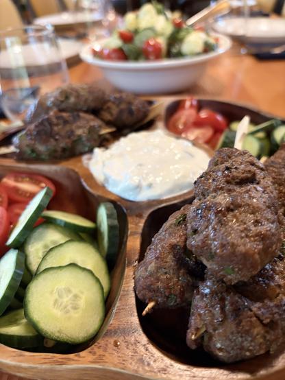Kofta with yogurt dip, tomatoes and capsicum, it is a timber divided plate. A central cavity and four quarters.